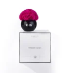 Sleek black glass vase holding vibrant deep magenta rose bouquet on white rectangular box with minimalist design