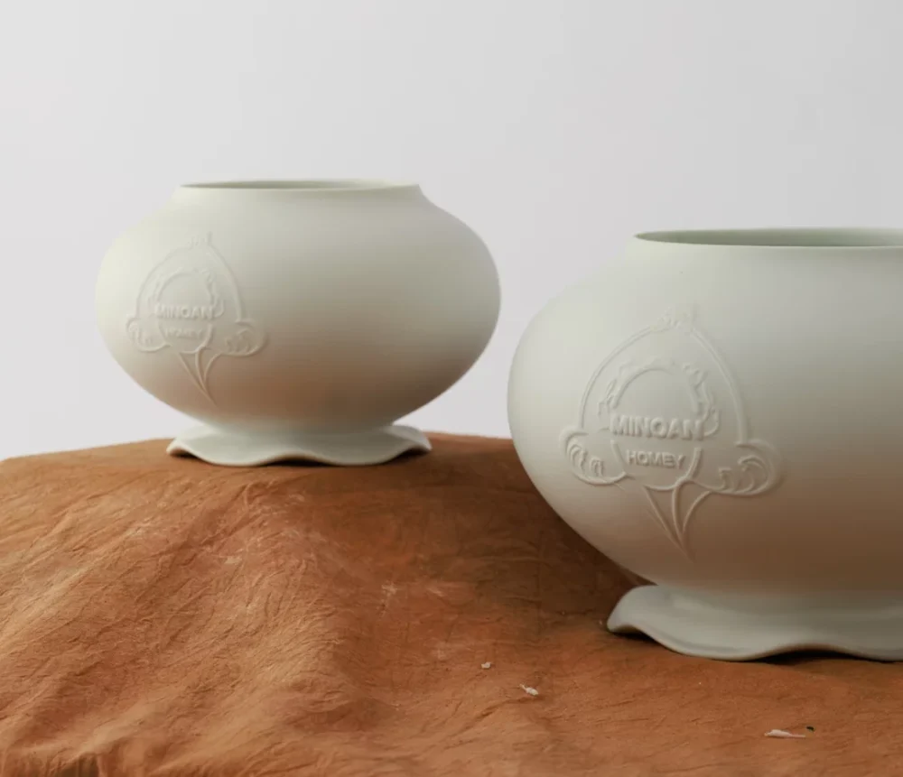 Two pale green ceramic vases with flower designs
