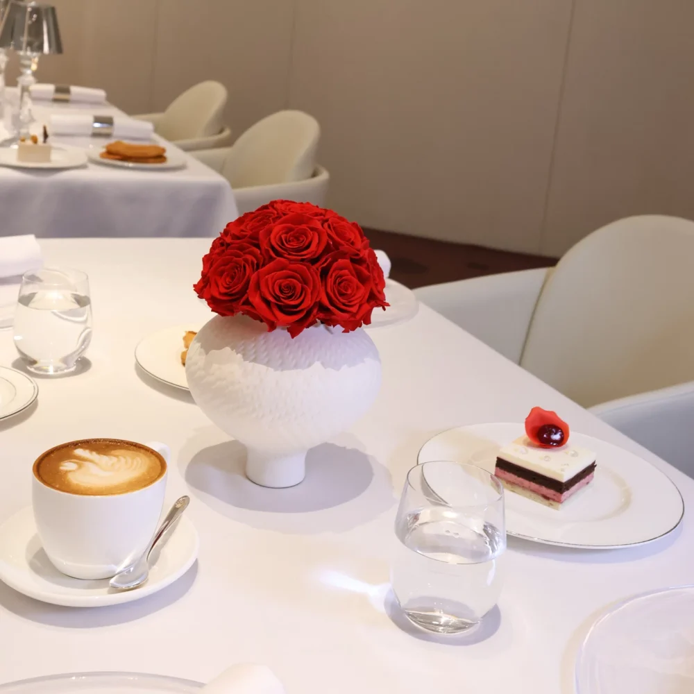 Elegant minimalist table with white ceramic vase containing red roses bouquet