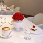 Elegant minimalist table with white ceramic vase containing red roses bouquet