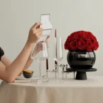 Minimalist elegant table with black vase of red roses, wine glasses, and red candles