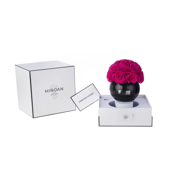 Minimalist white gift box with black rim containing glossy black vase filled with vibrant magenta roses